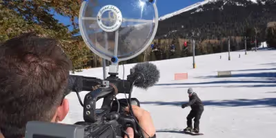 a cameraman filming a snowboarder with a Sound Shark long-range mic on his video camera