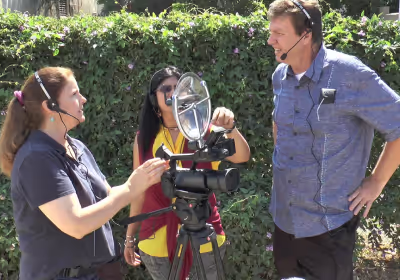 an group standing around a KLOVER MiK 09 parabolic microphone mounted on a video camera